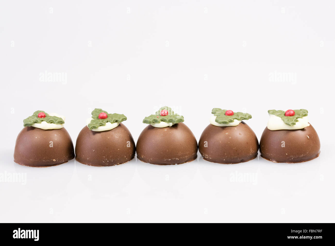 Five Chocolate christmas puddings on a white background. Stock Photo