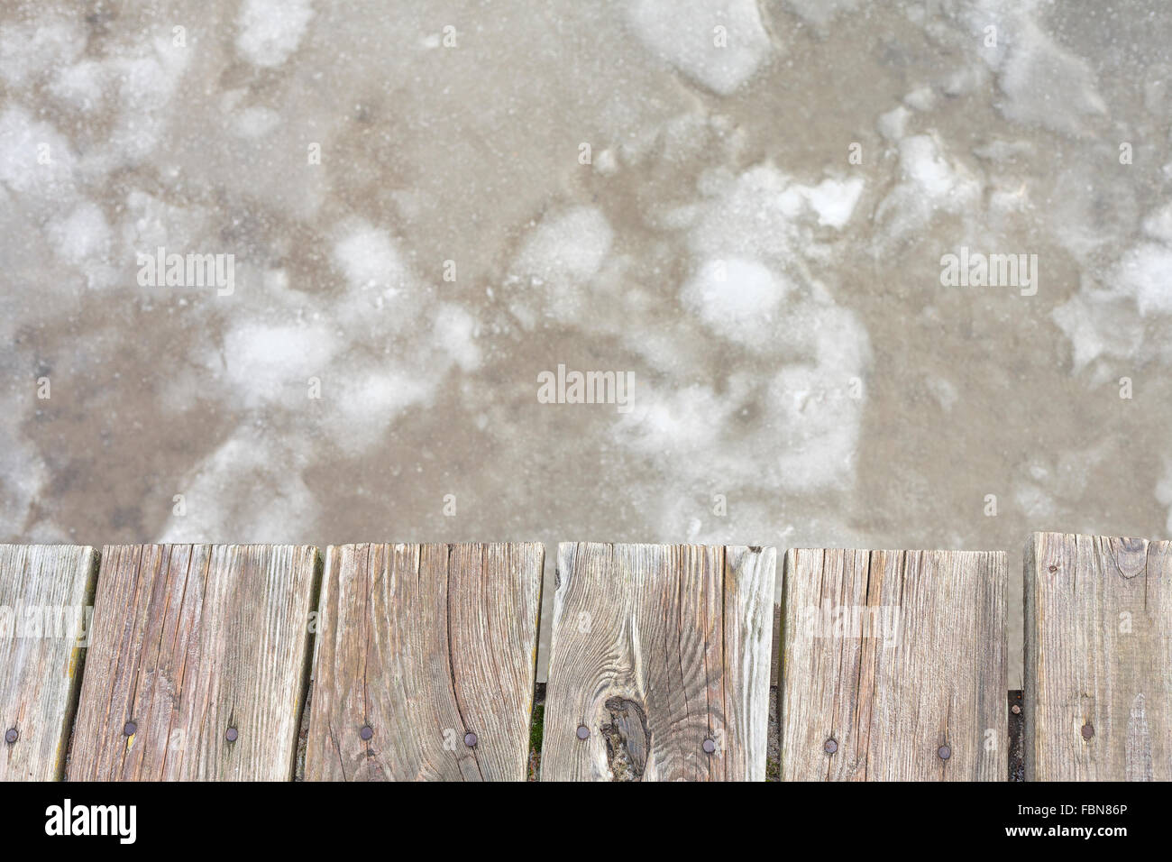Old wooden pier on ice, abstract background with space for text. Stock Photo