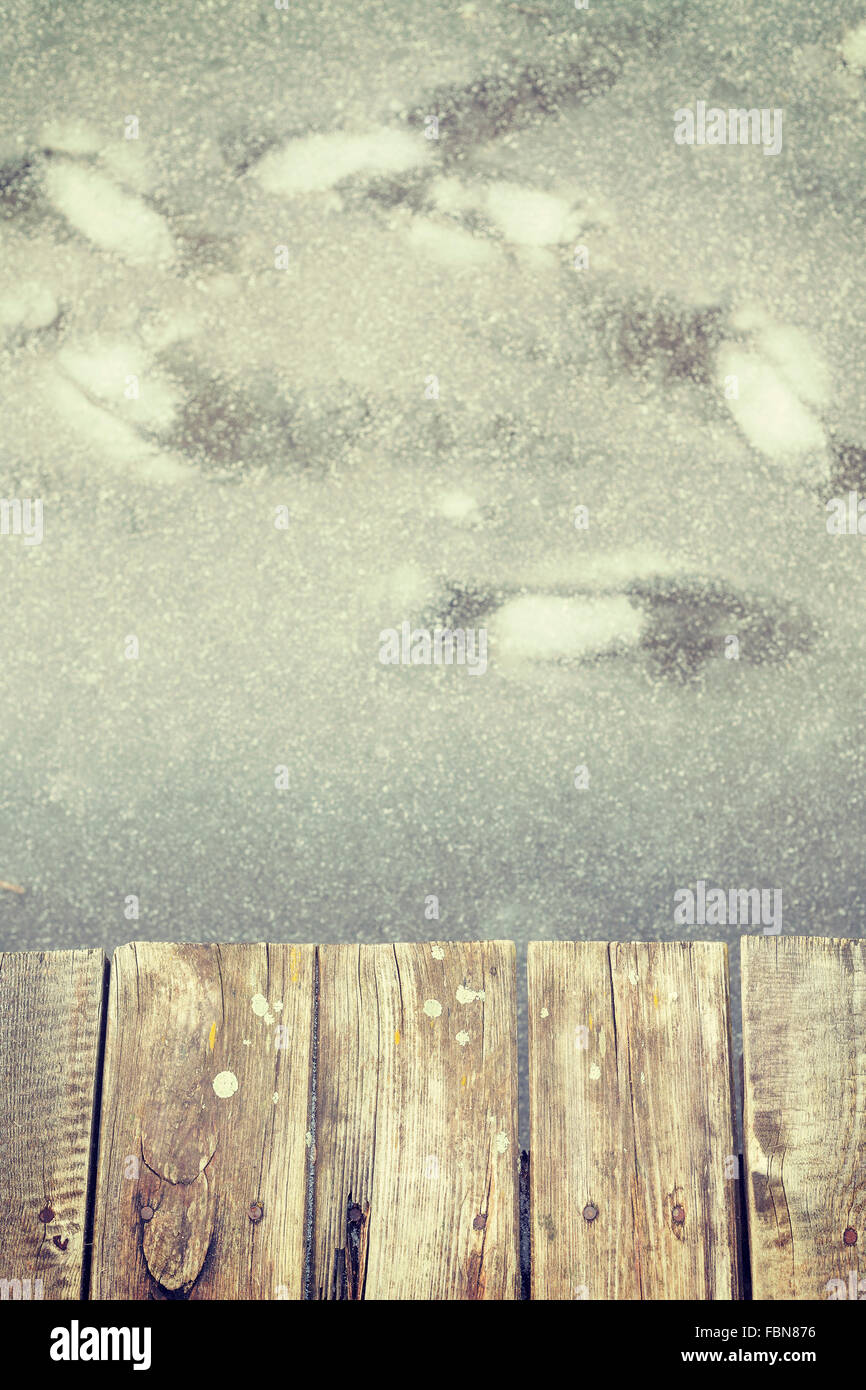 Retro toned old wooden pier on ice, abstract background with space for text. Stock Photo