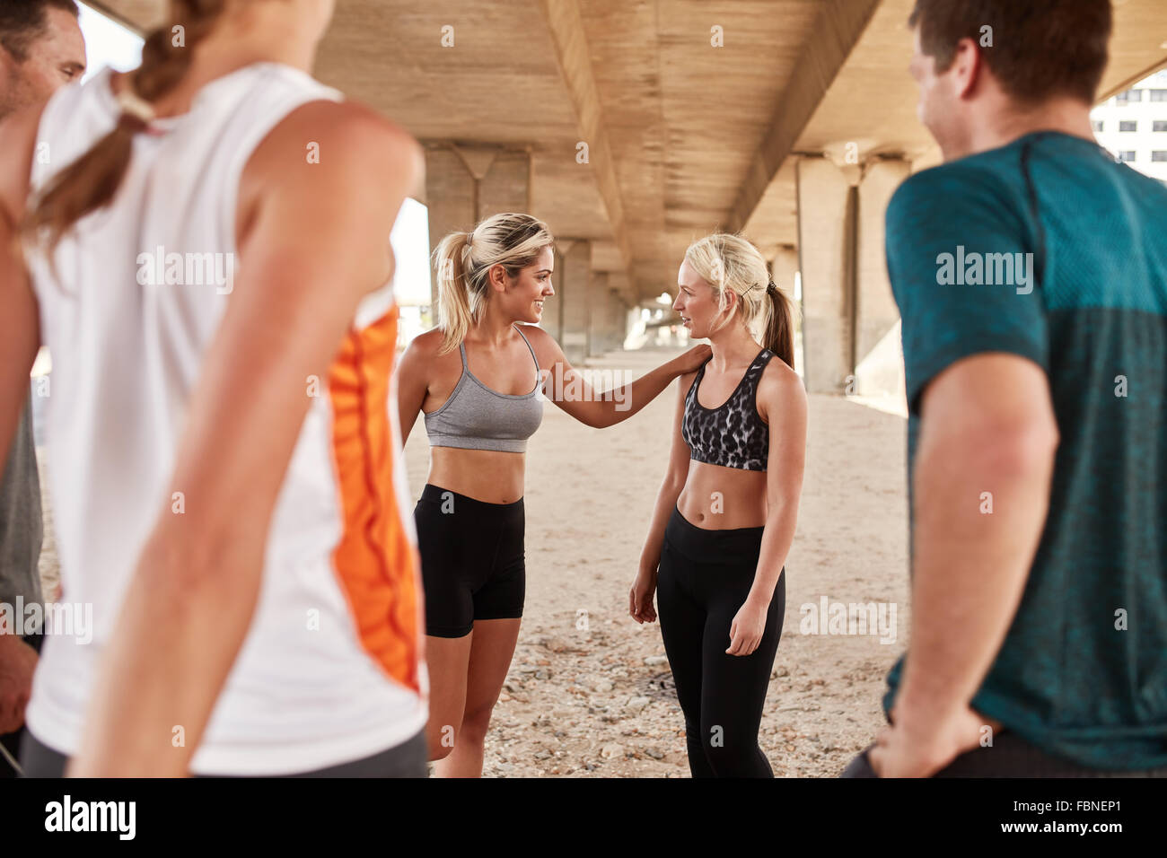 Young people taking break in running training. Athletes relaxing and talking after a morning run. Stock Photo