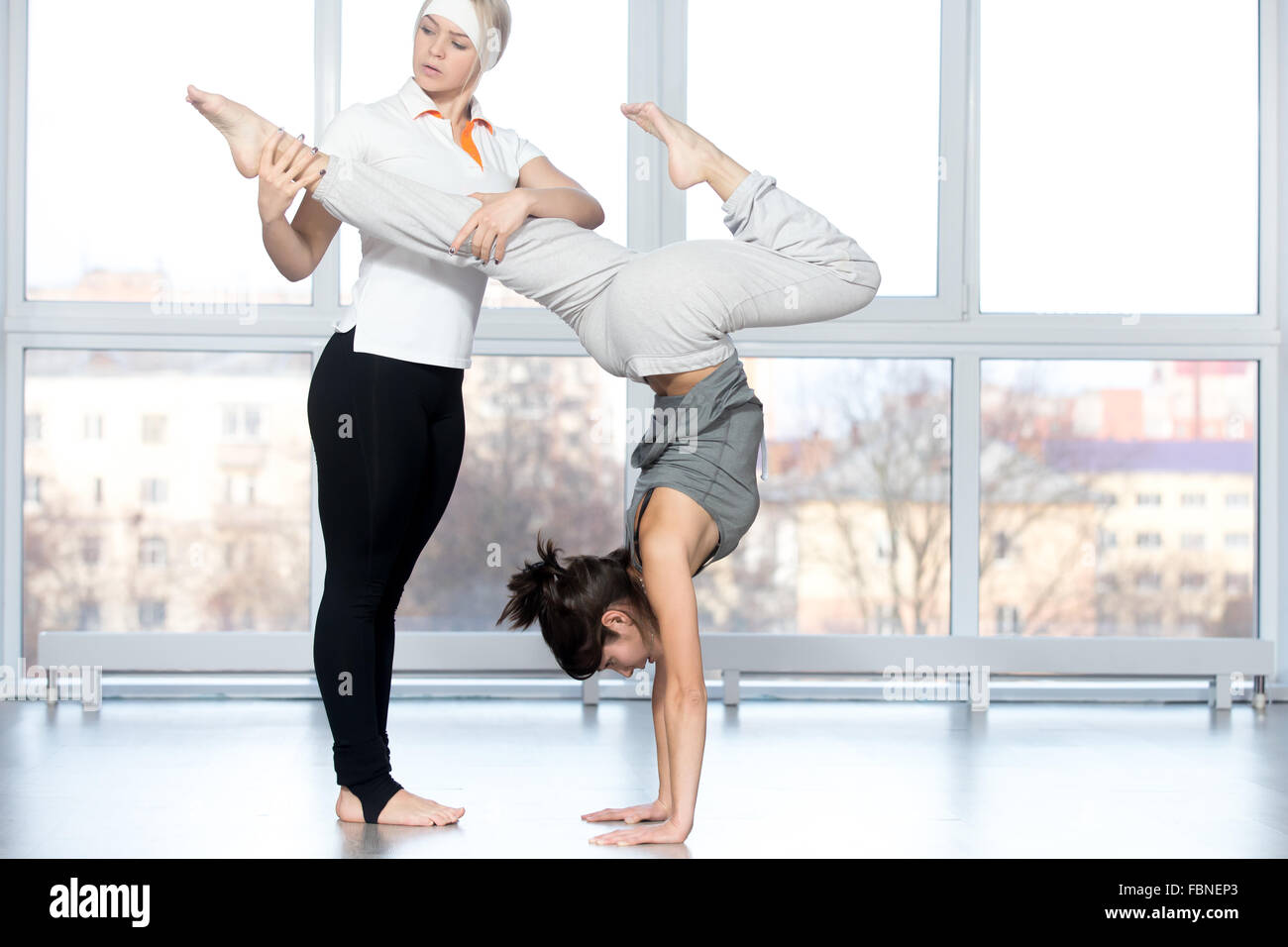 Fitness practice, instructor helping young beautiful student female to ...