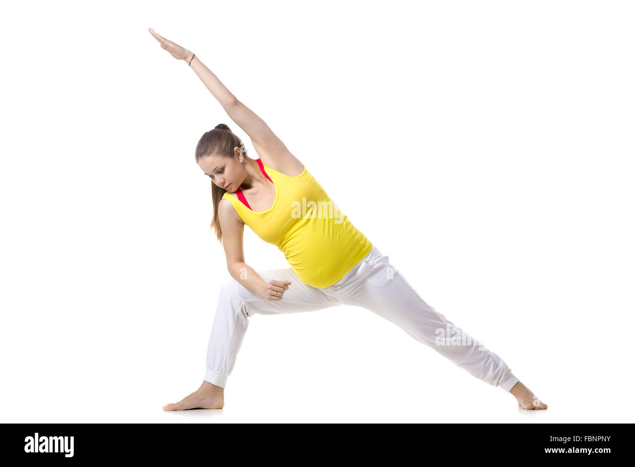 Full length portrait of young pregnant fitness model in sportswear doing yoga, pilates training, lunge exercise, Utthita Stock Photo