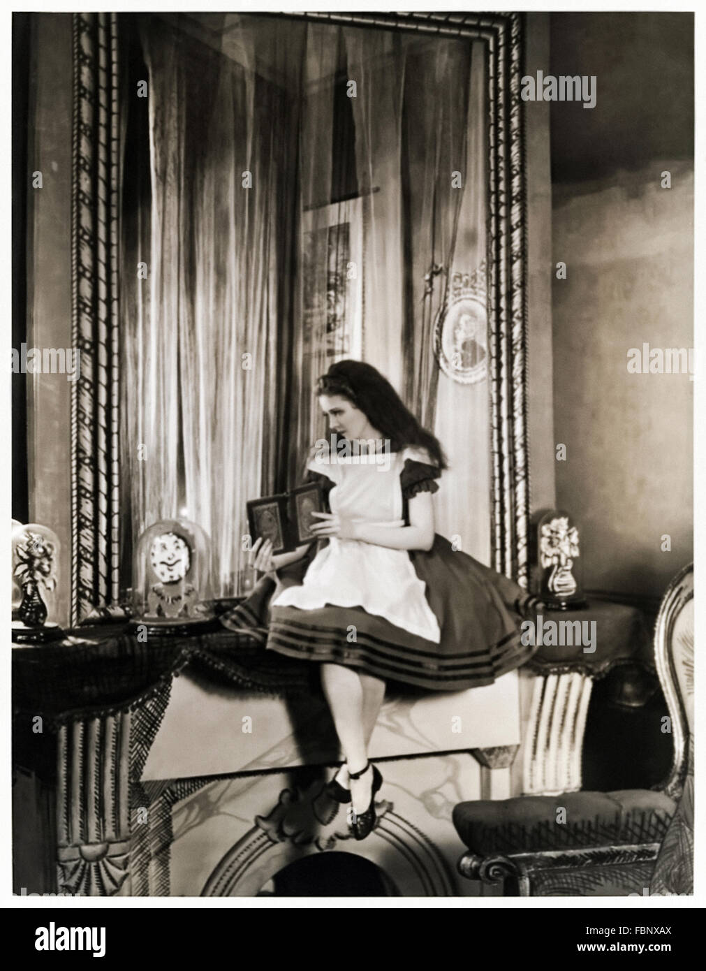 Alice besides the looking glass, publicity photograph for the 1932 stage adaptation of 'Alice in Wonderland' by Lewis Carroll (1832-1898) starring Josephine Hutchinson (1903-1998) as Alice. Stock Photo
