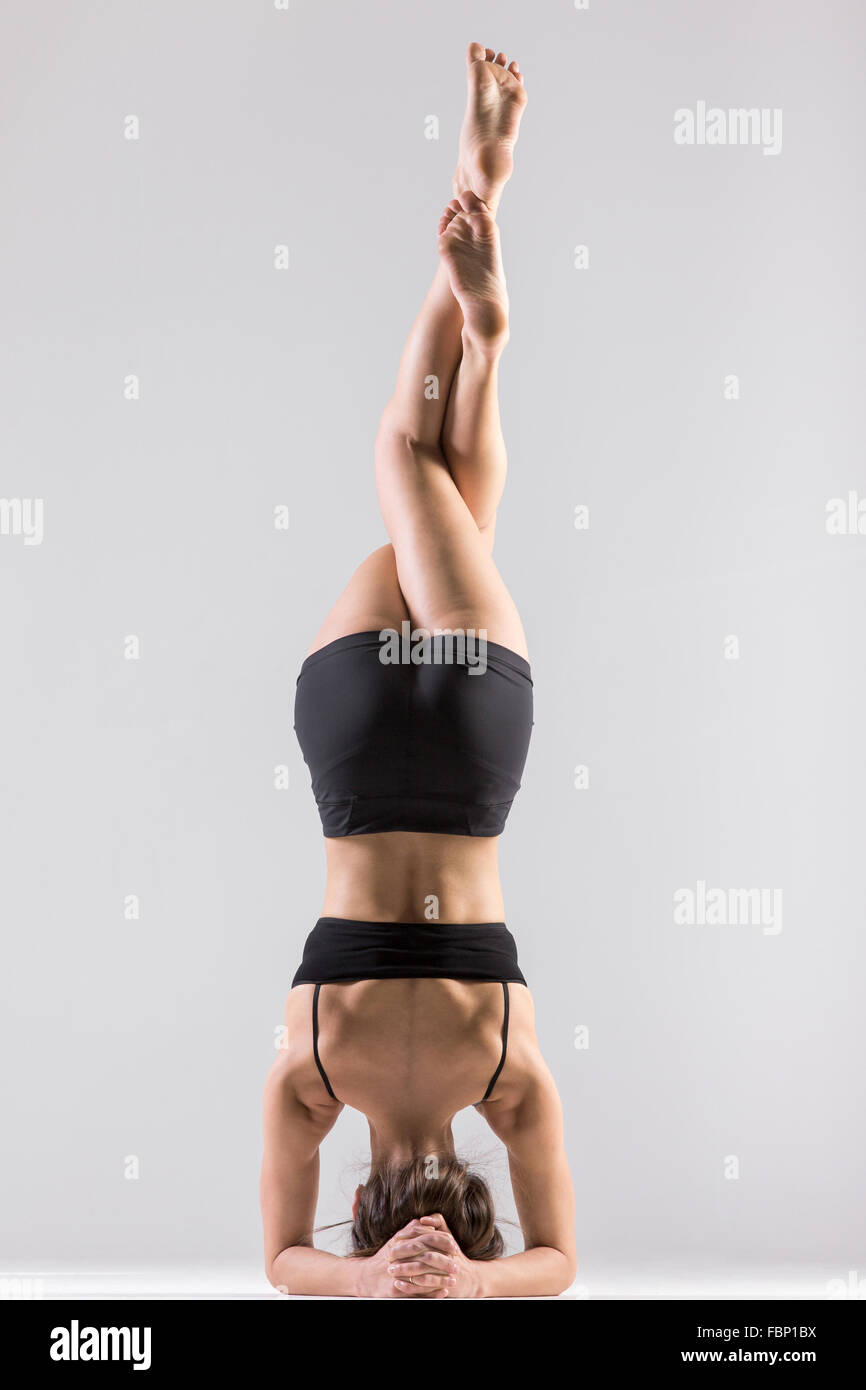 Sporty girl doing Supported Headstand, yoga asana Sirsasana, Shirshasana, Sirshasana, Headstand with crossed legs Stock Photo
