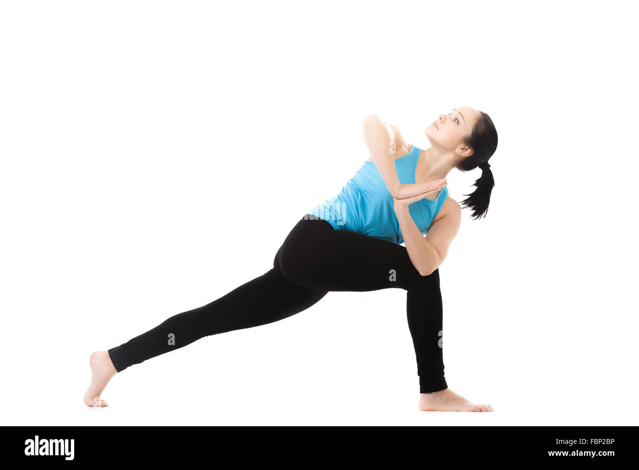 Sporty yoga girl exercises on white background in parivritta parshvakonasana (revolved side angle pose), palms in Namaste Stock Photo