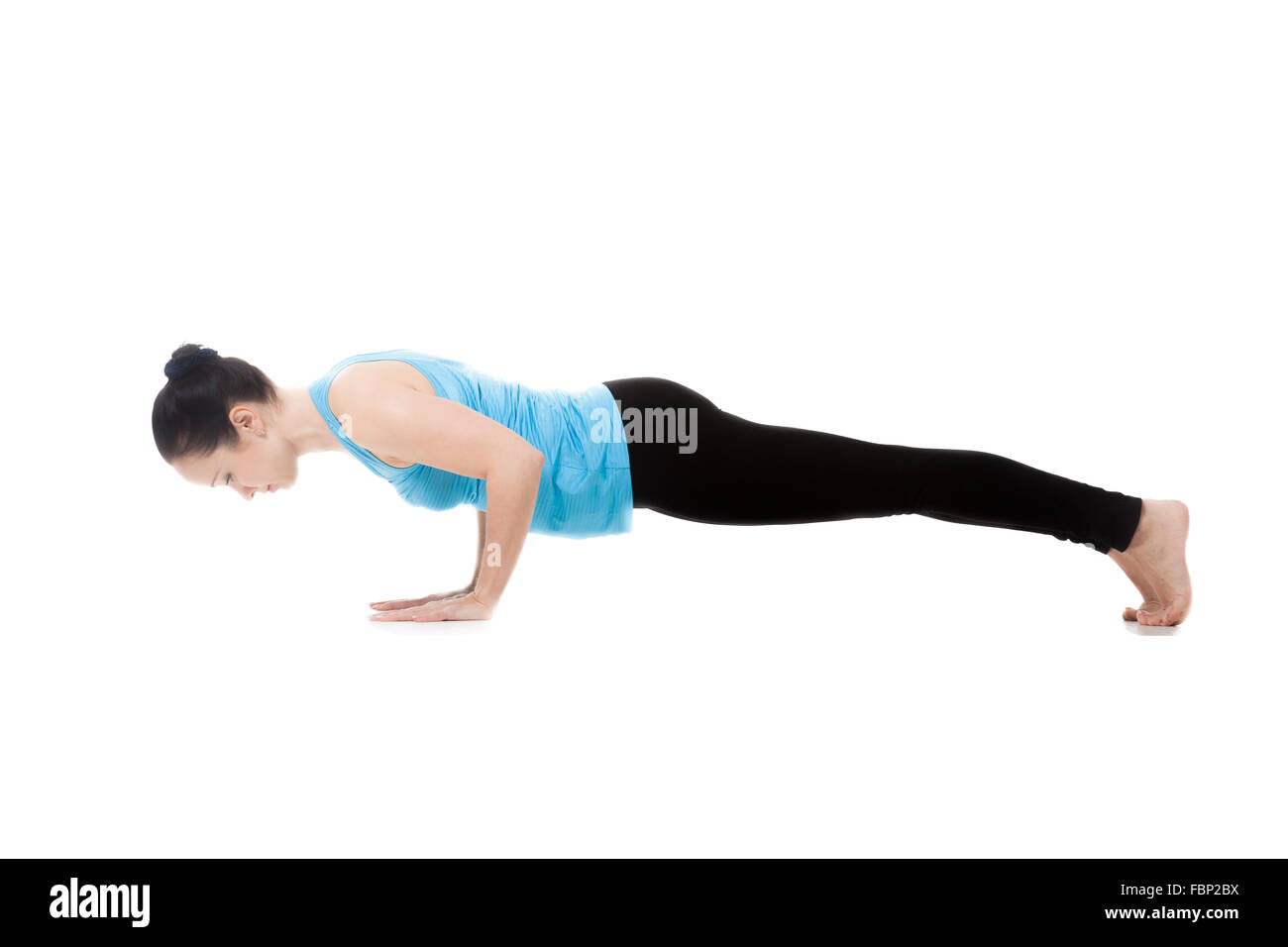 Sporty yogi girl doing yoga exercises, push-ups, pose Chaturanga Dandasana (Four-Limbed Staff Pose), isolated Stock Photo