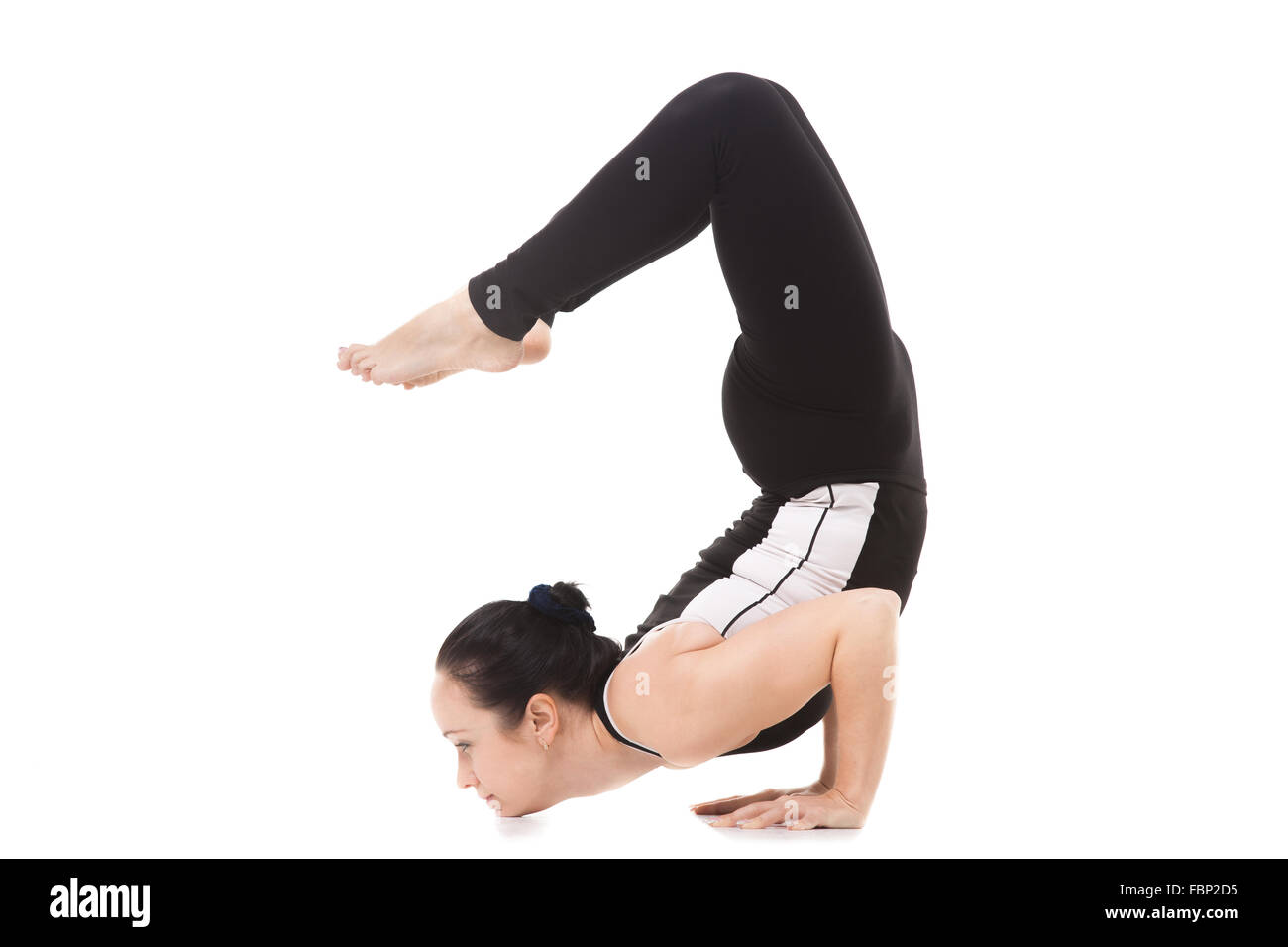 Sporty yogi girl doing fitness exercises, yoga asana Scorpion Pose Vrischikasana posture, forearm stand, inverted backbend pose Stock Photo