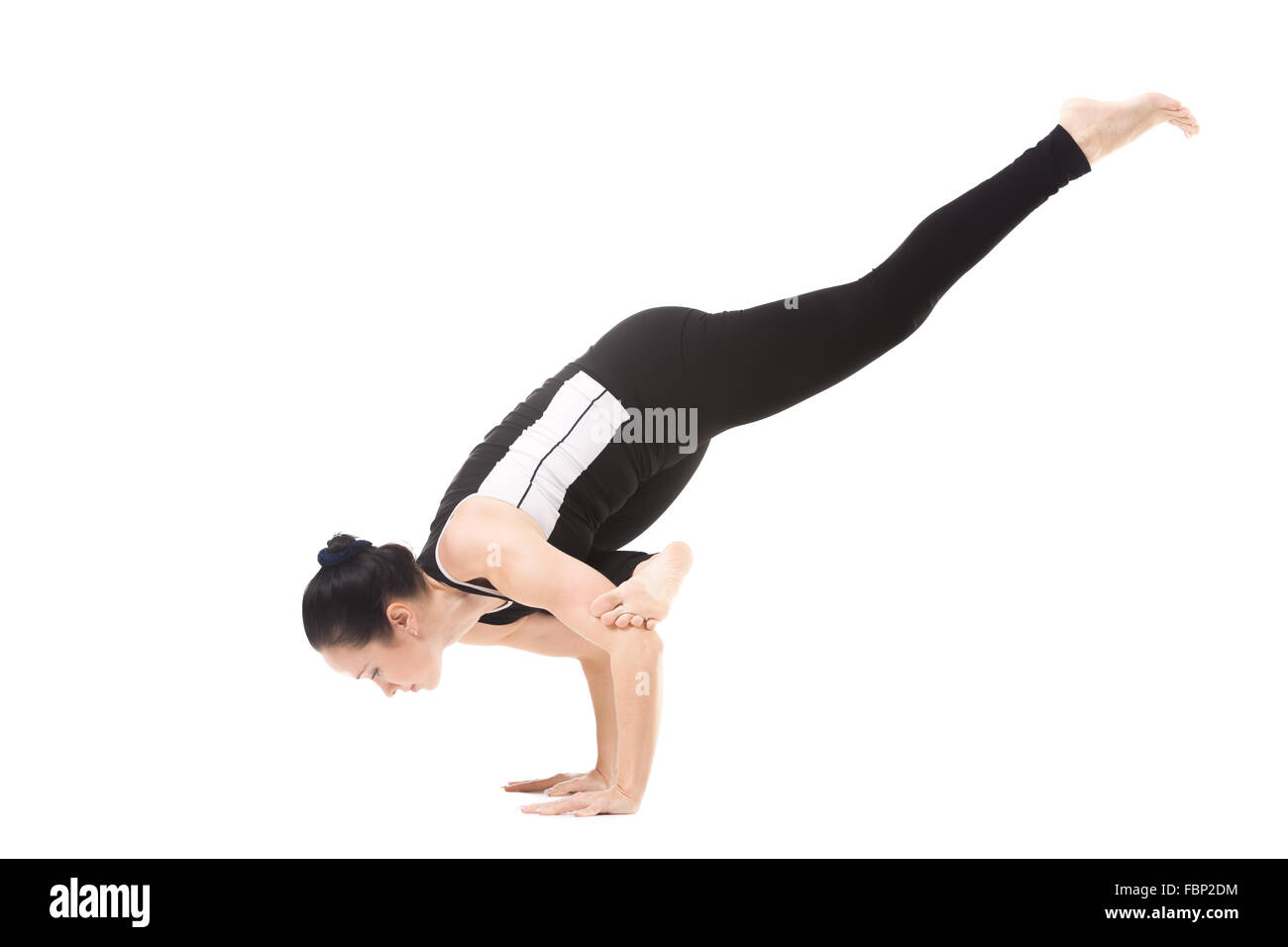 Sporty yoga girl doing fitness training, asana Eka Pada Galavasana, Flying Pigeon (flying crow) Pose, One-Legged Balance Stock Photo