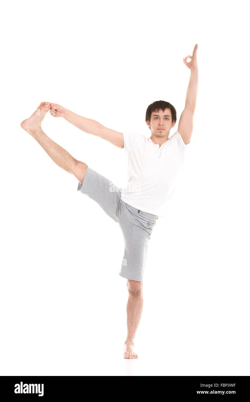Sporty young man working out, yoga, pilates, fitness training, standing in yoga asana utthita hasta Padangustasana, extended Stock Photo