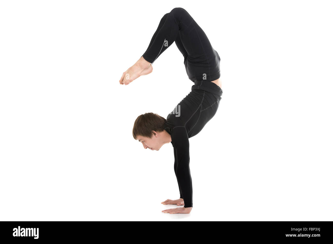 Profile of sporty yogi male doing fitness exercises, yoga asana Scorpion Pose Vrischikasana 2, handstand, inverted backbend pose Stock Photo