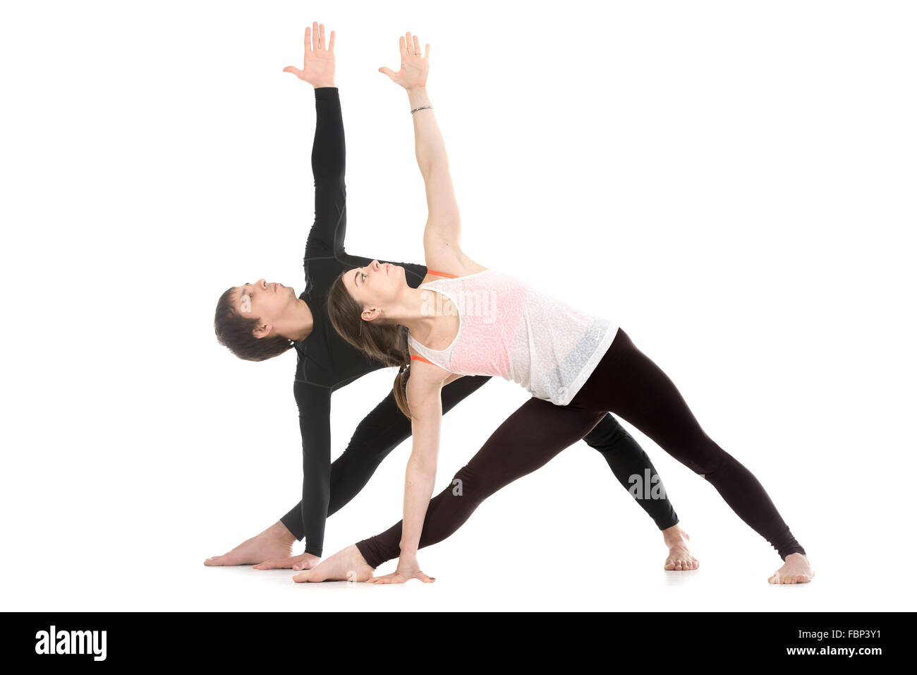 Two sporty people practice yoga with partner, couple doing stretching exercise, extended triangle pose, utthita trikonasana Stock Photo