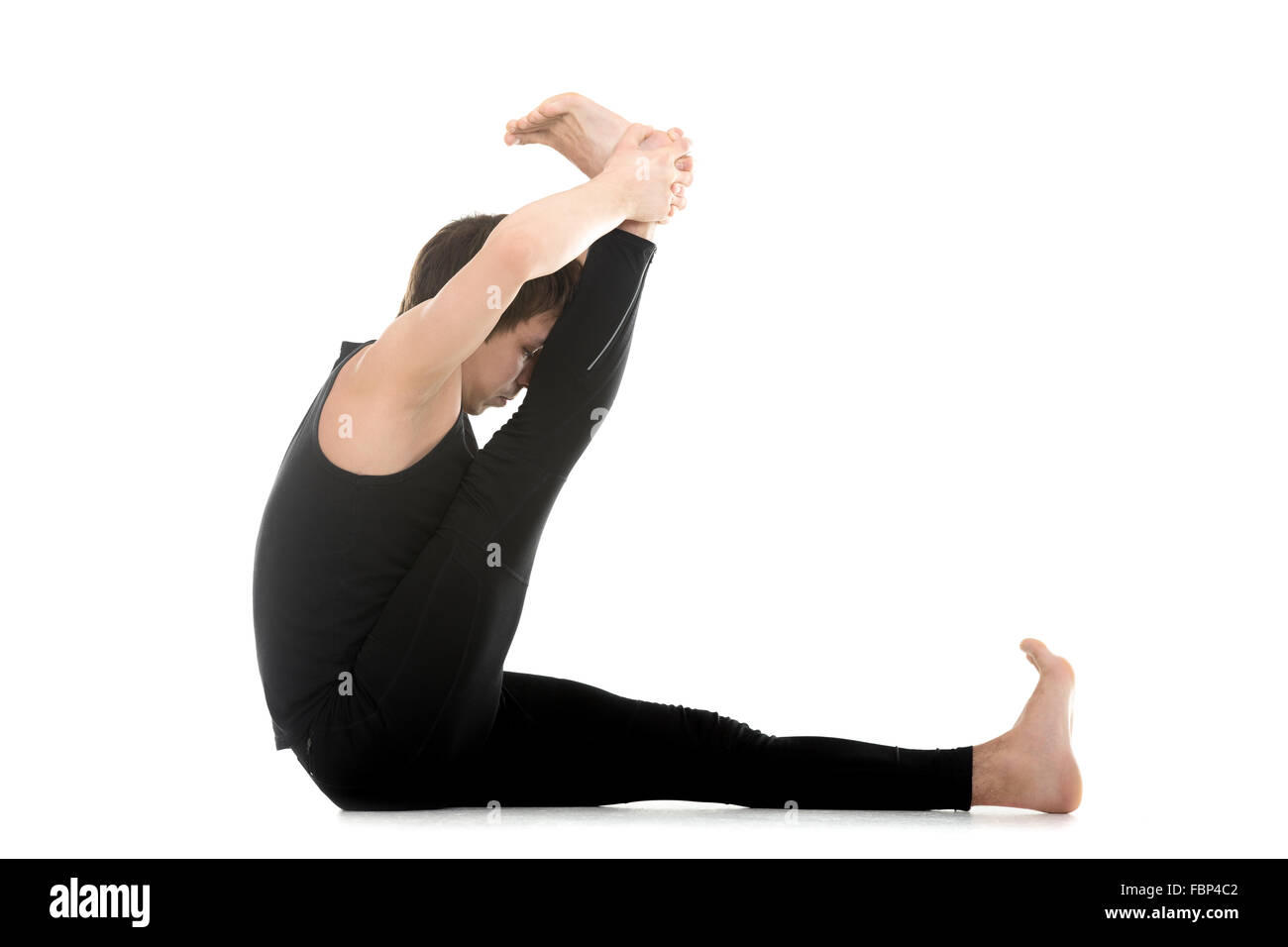 Sporty attractive young man working out, doing yoga, pilates or fitness training, stretching exercises, heron pose variation Stock Photo