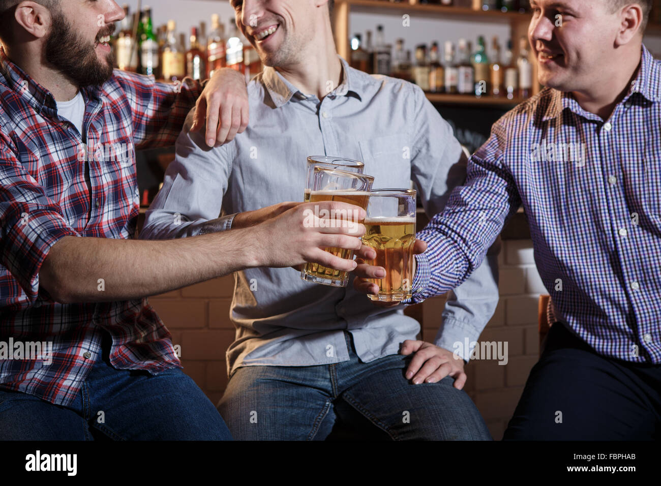 Happy friends drinking beer at counter in pub Stock Photo