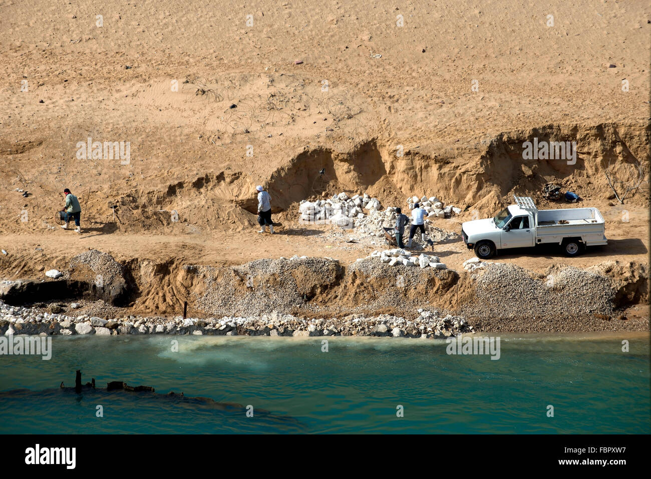 Egyptian workers work at a construction site on the banks of the new waterway of the Suez Canal. Stock Photo
