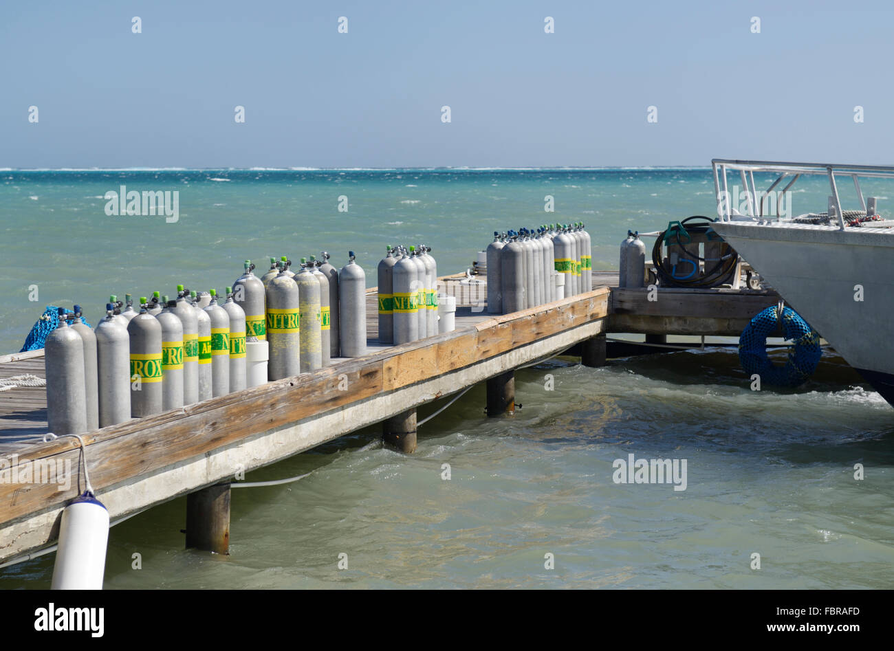 Compressed air tanks for SCUBA lined up on dock.  Many are Nitrox which is a higher concentration of oxygen Stock Photo