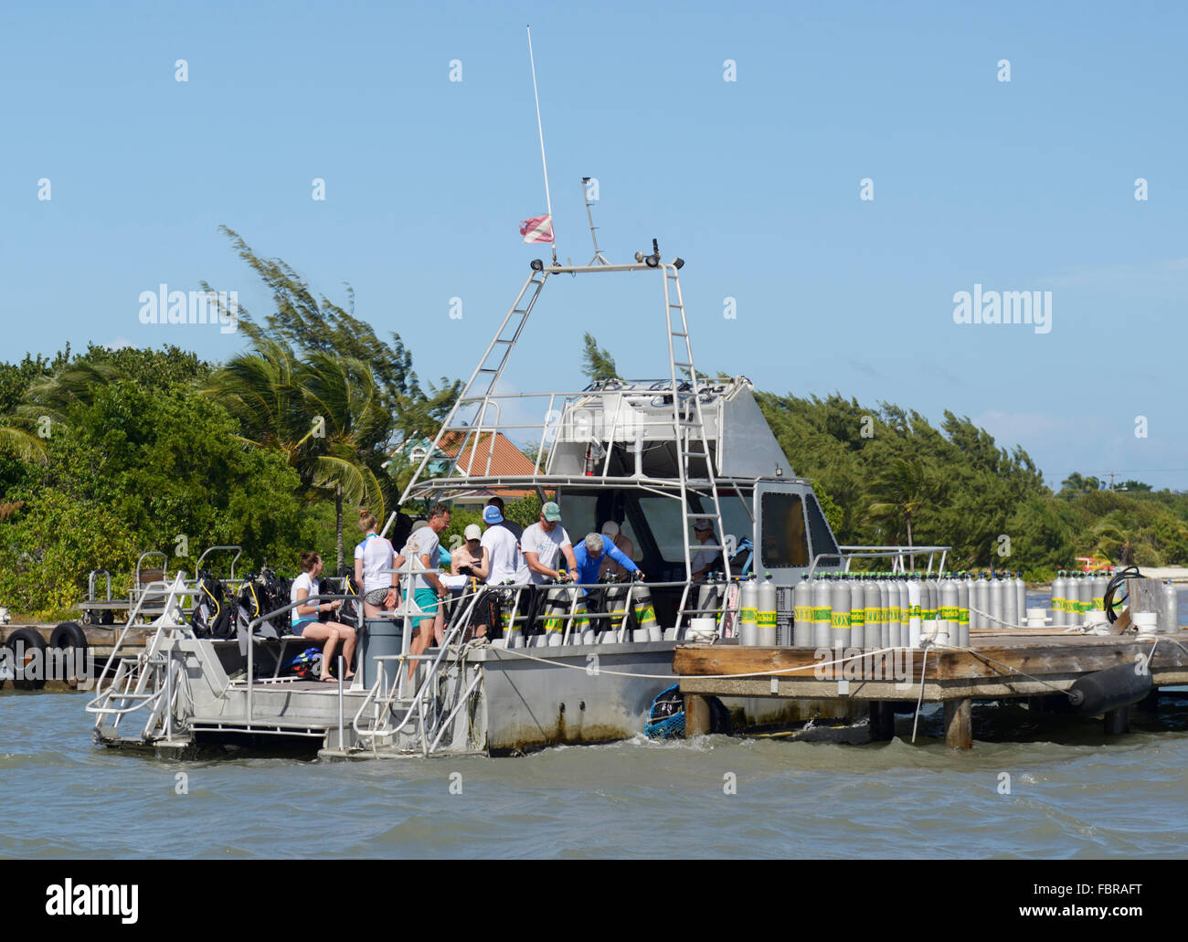 Dive boat with divers preparing to depart the dock and air tanks lined up on dock, Ocean frontiers, East End, Grand Cayman Stock Photo