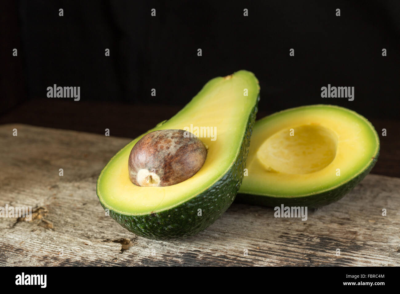 Halved avocado on old wooden board. Close up image Stock Photo - Alamy