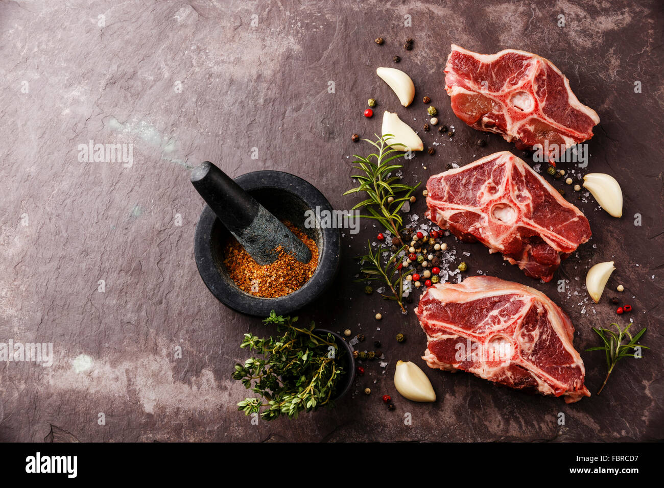 Raw fresh lamb loin chops with herbs and spices on stone slate plate Stock Photo