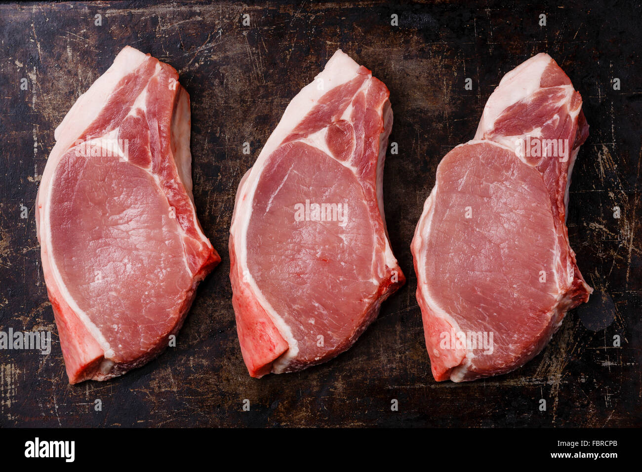 Raw fresh uncooked Pork meat chop steak on bone on dark background Stock Photo