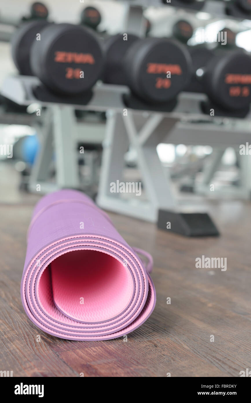 close up of rolled yoga mat on a wooden floor in gym. Stock Photo