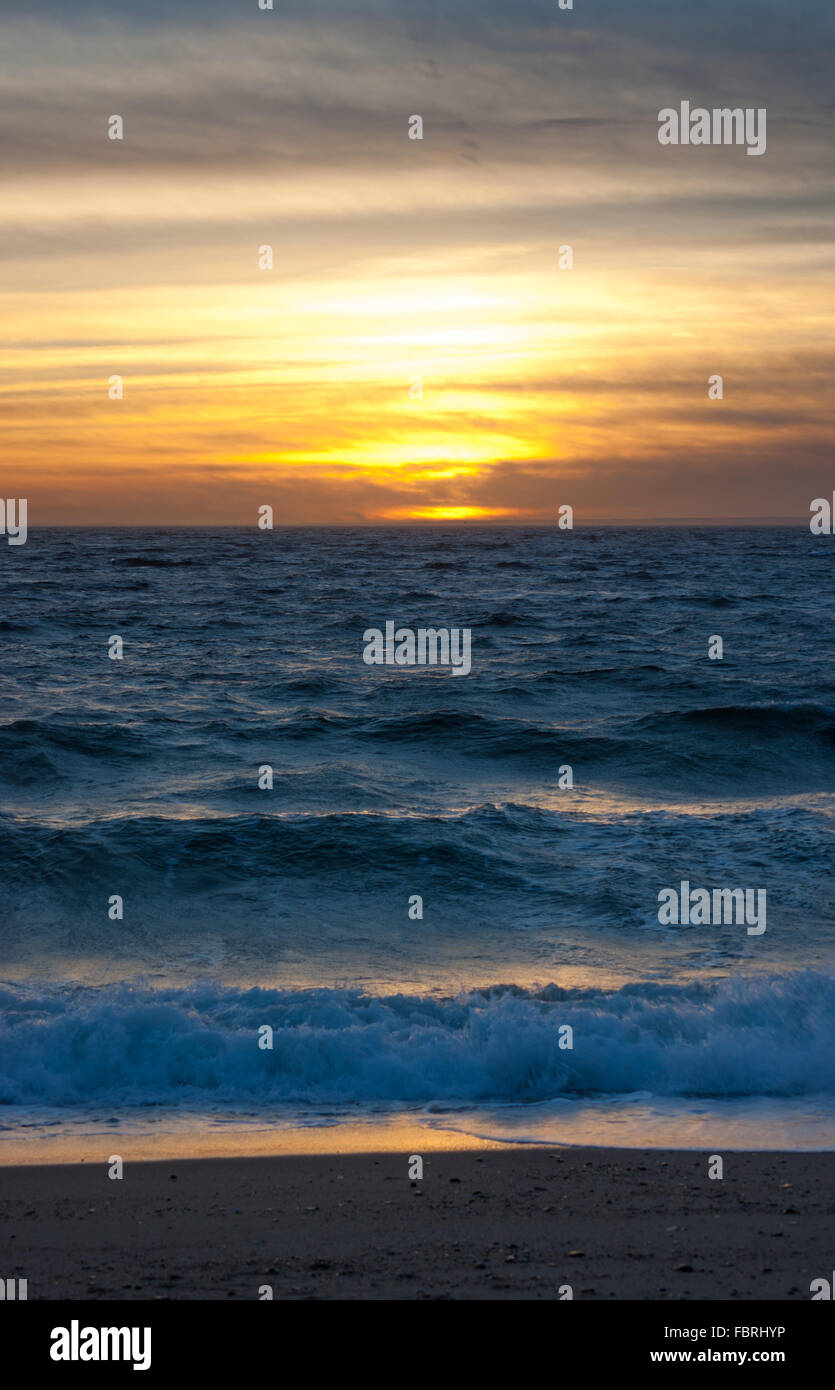 Colorful sunset over the ocean with waves breaking on shore at Herring