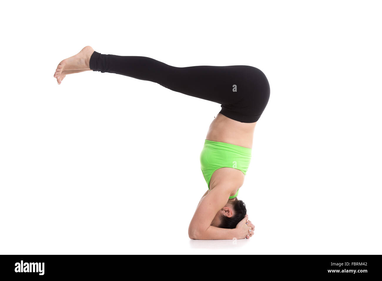 Beautiful sporty girl doing yoga exercises for abdominal muscles, flat belly, supported headstand yoga asana, salamba sirsasana Stock Photo
