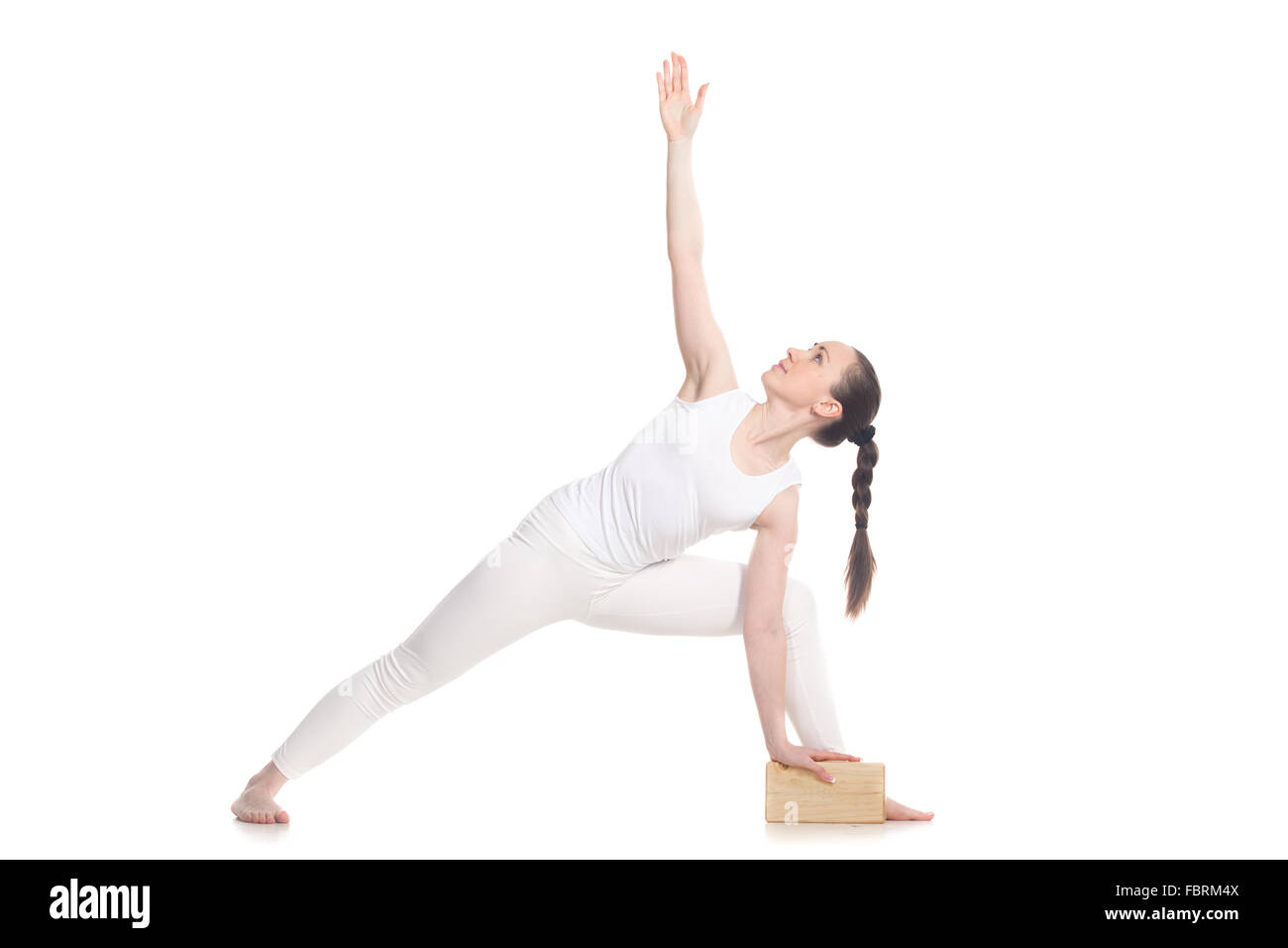 Sporty attractive young woman in white sportswear doing lunge exercise for back, utthita parsva konasana with wooden block Stock Photo