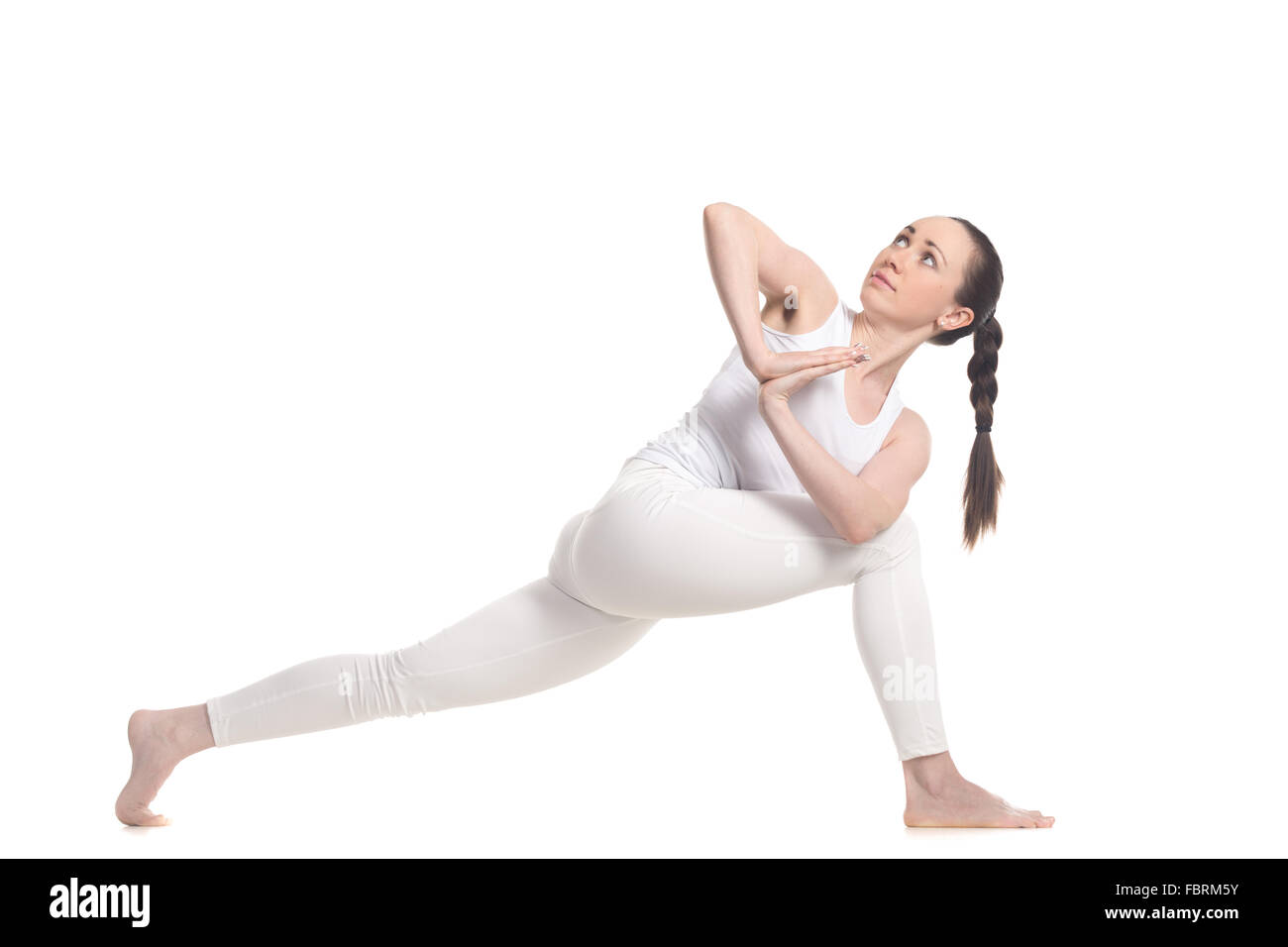 Sporty beautiful young woman in white sportswear doing lunge exercise for spine, standing in variation of Revolved Side Angle Stock Photo