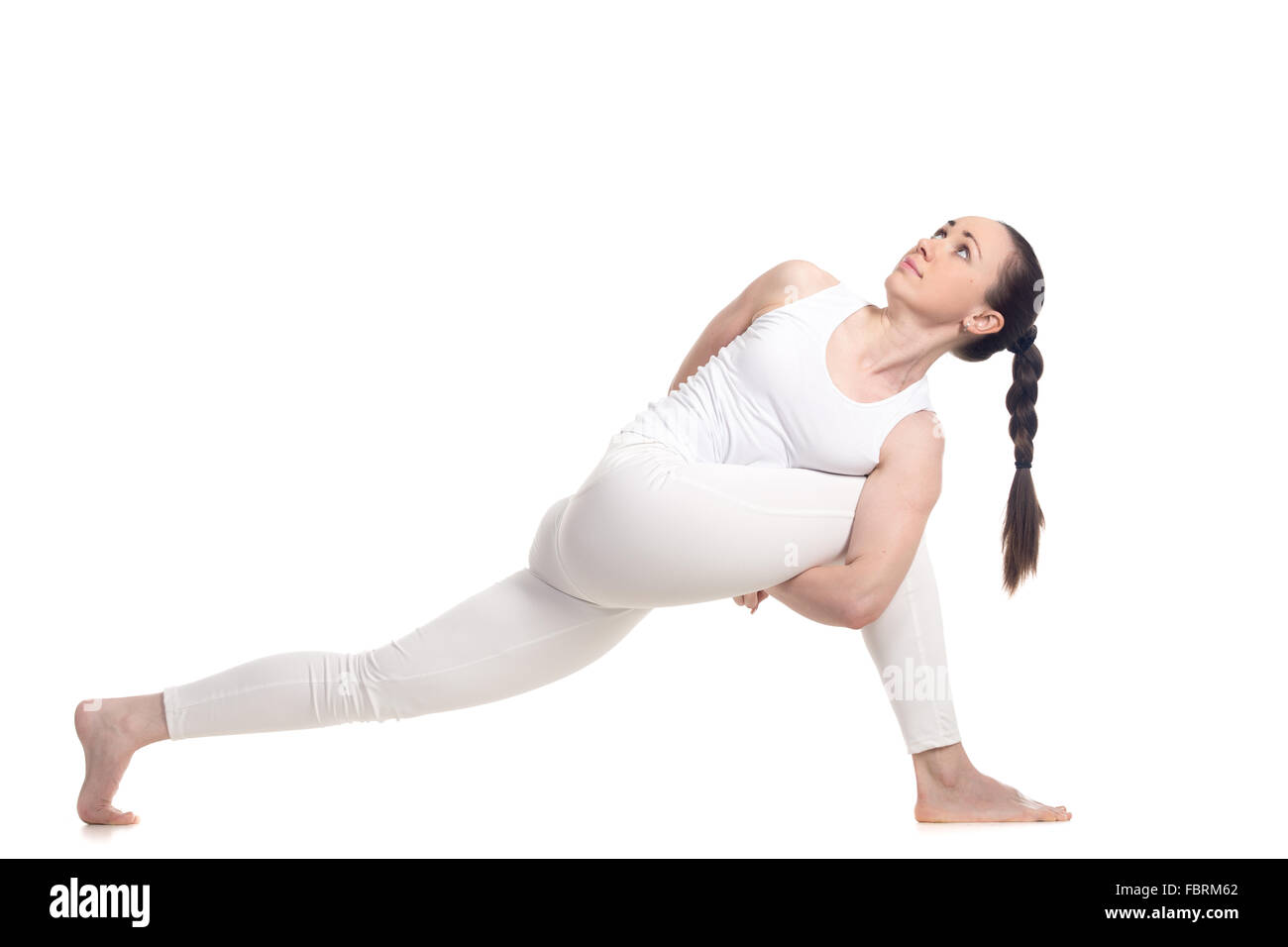 Sporty beautiful young woman in white sportswear doing lunge exercise for spine flexibility, standing in parivritta parshvakonas Stock Photo