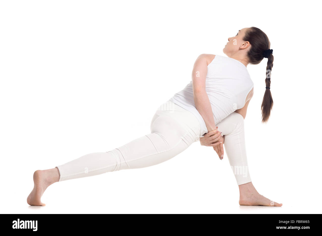 Sporty beautiful young woman in white sportswear doing lunge exercise for spine, standing in parivritta parshvakonasana Stock Photo