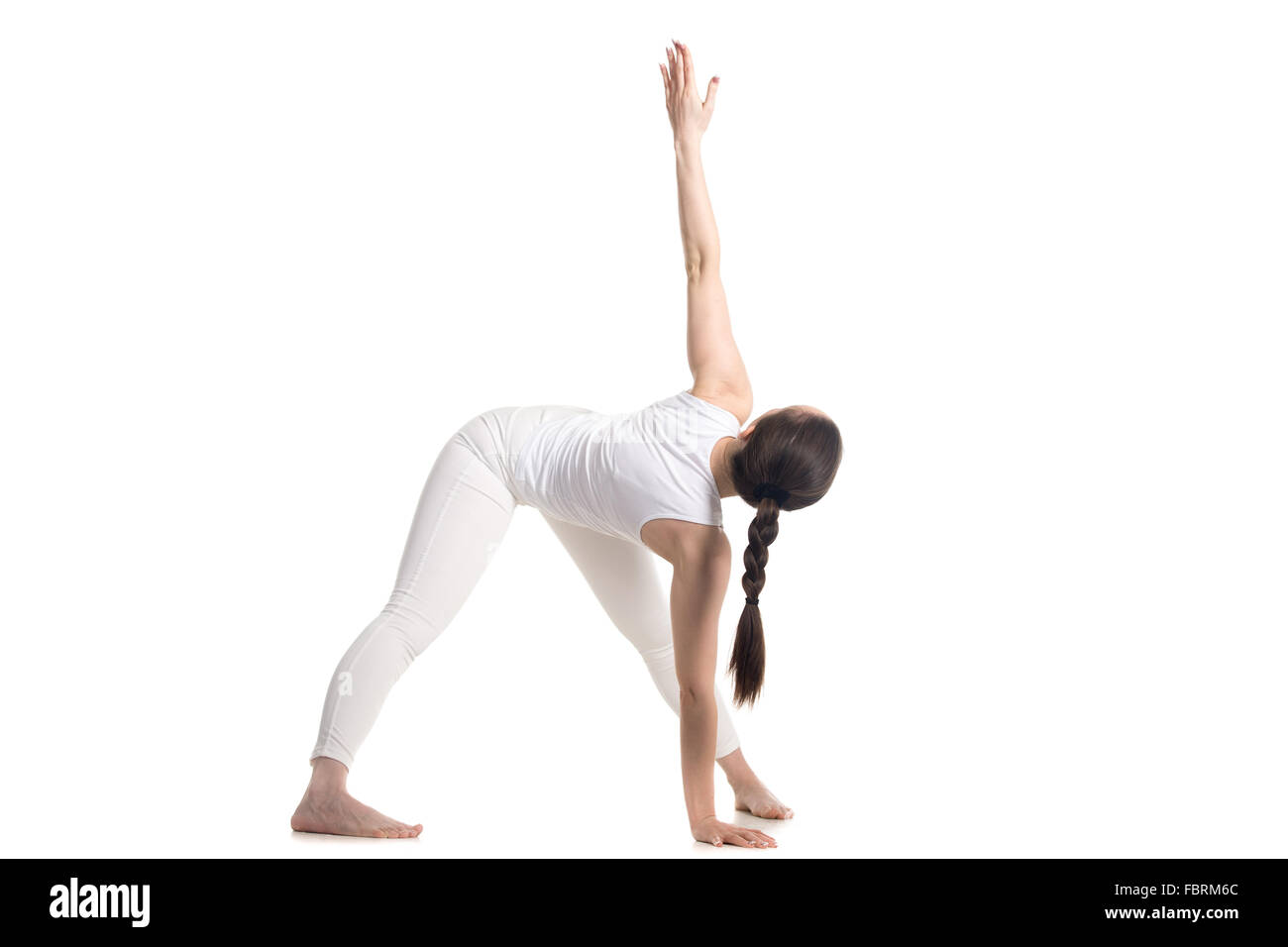 Sporty beautiful young woman in white sportswear standing in variation of Triangle yoga pose, studio full length three-quarters Stock Photo