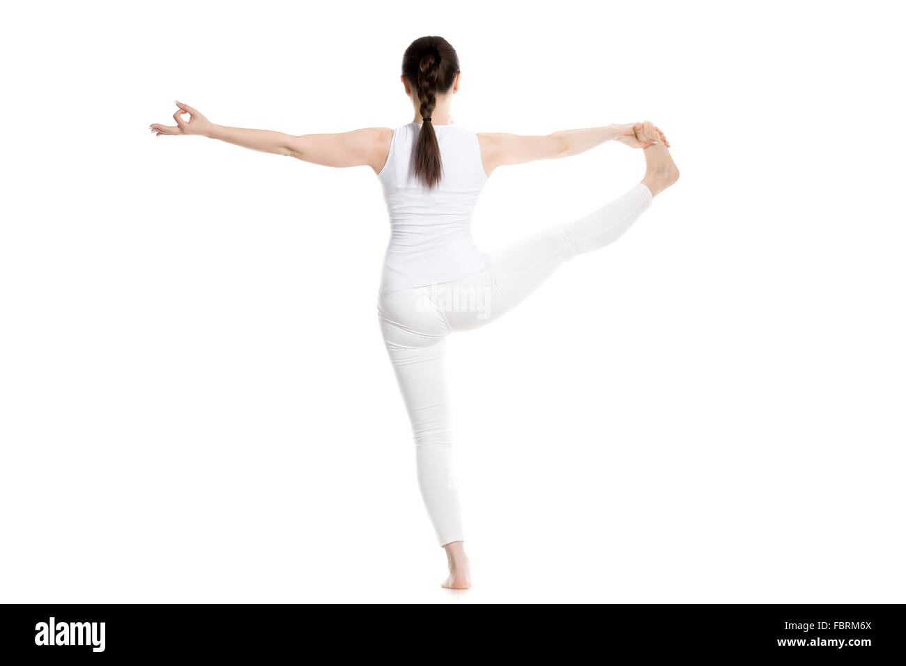 Sporty beautiful young woman in white sportswear standing in Utthita Hasta Padangushthasana, Extended Hand-To-Big-Toe yoga pose Stock Photo
