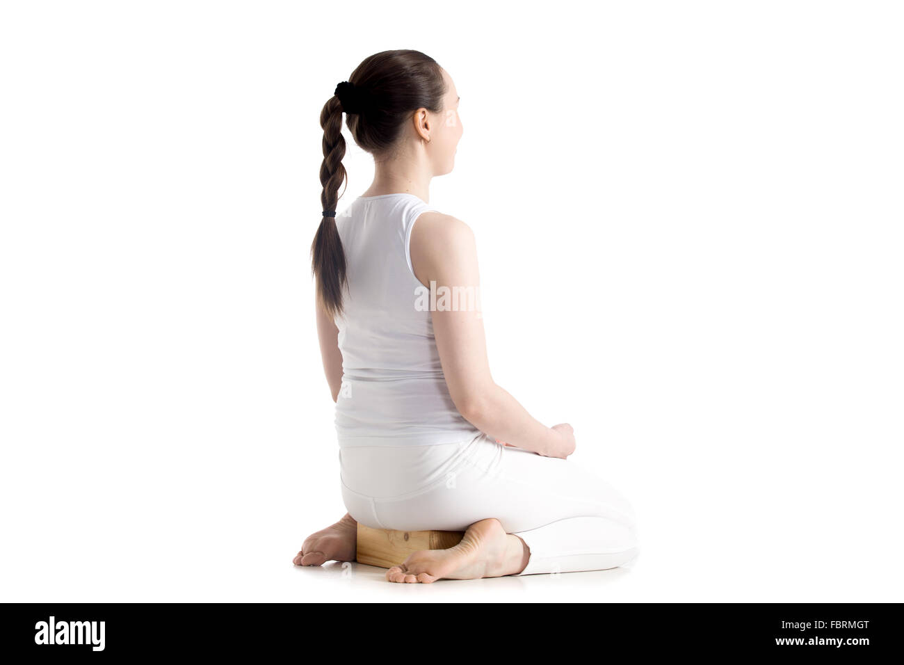 Sporty beautiful young woman practicing yoga, sitting on wooden block in seiza, vajrasana, thunderbolt or diamond asana Stock Photo