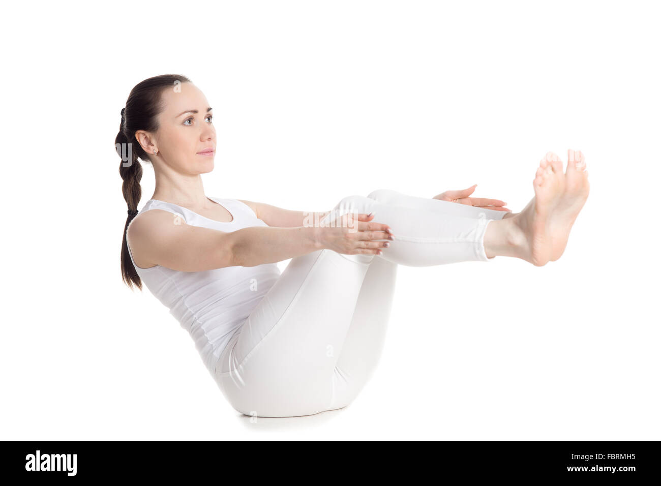 Sporty beautiful young woman in white sportswear doing exercises for back, hips and abdominal  muscles, sitting in navasana Stock Photo