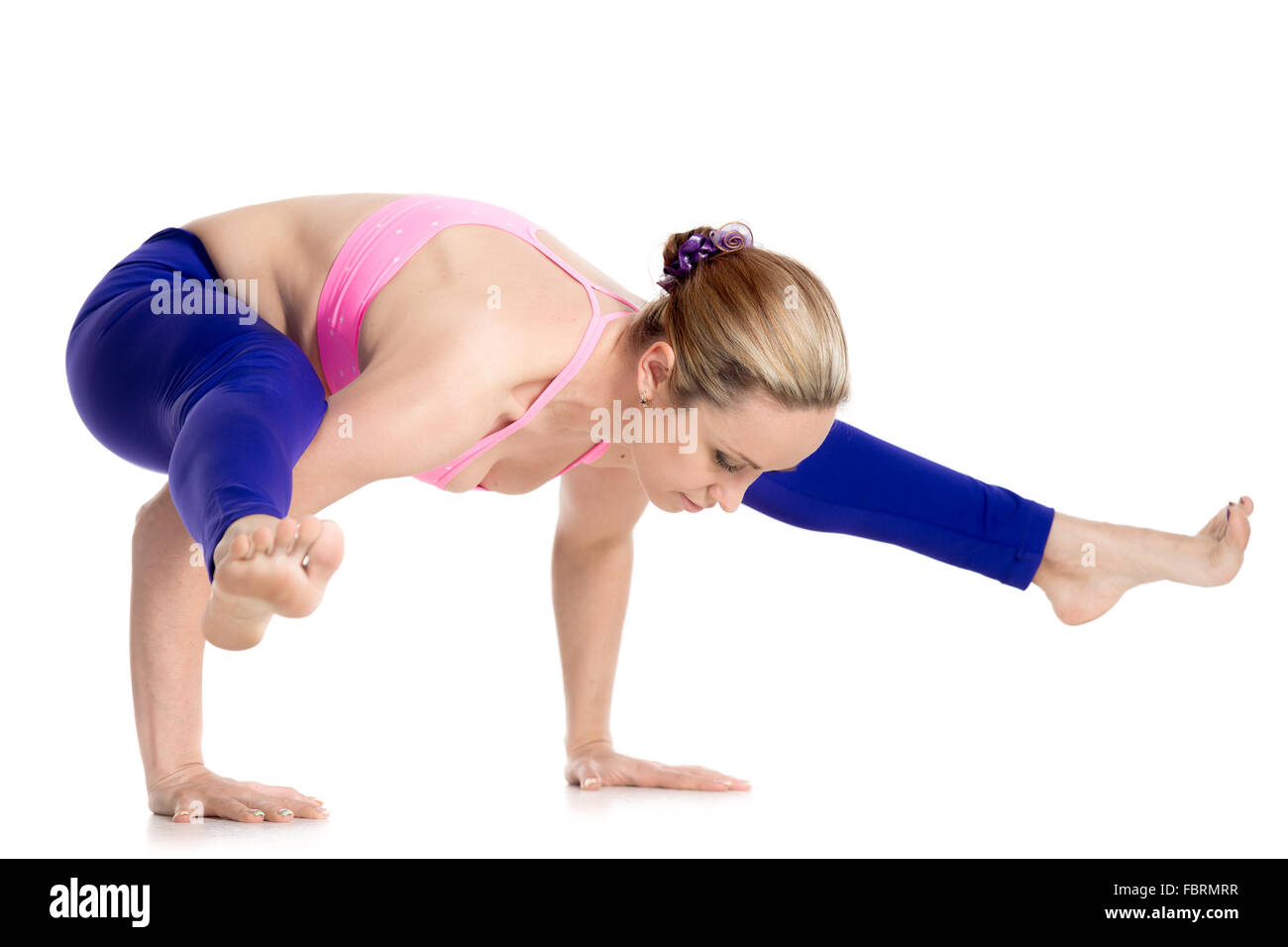Sporty beautiful blond young woman doing handstand, arm balance, variation of Firefly posture, asana Tittibhasana, studio Stock Photo