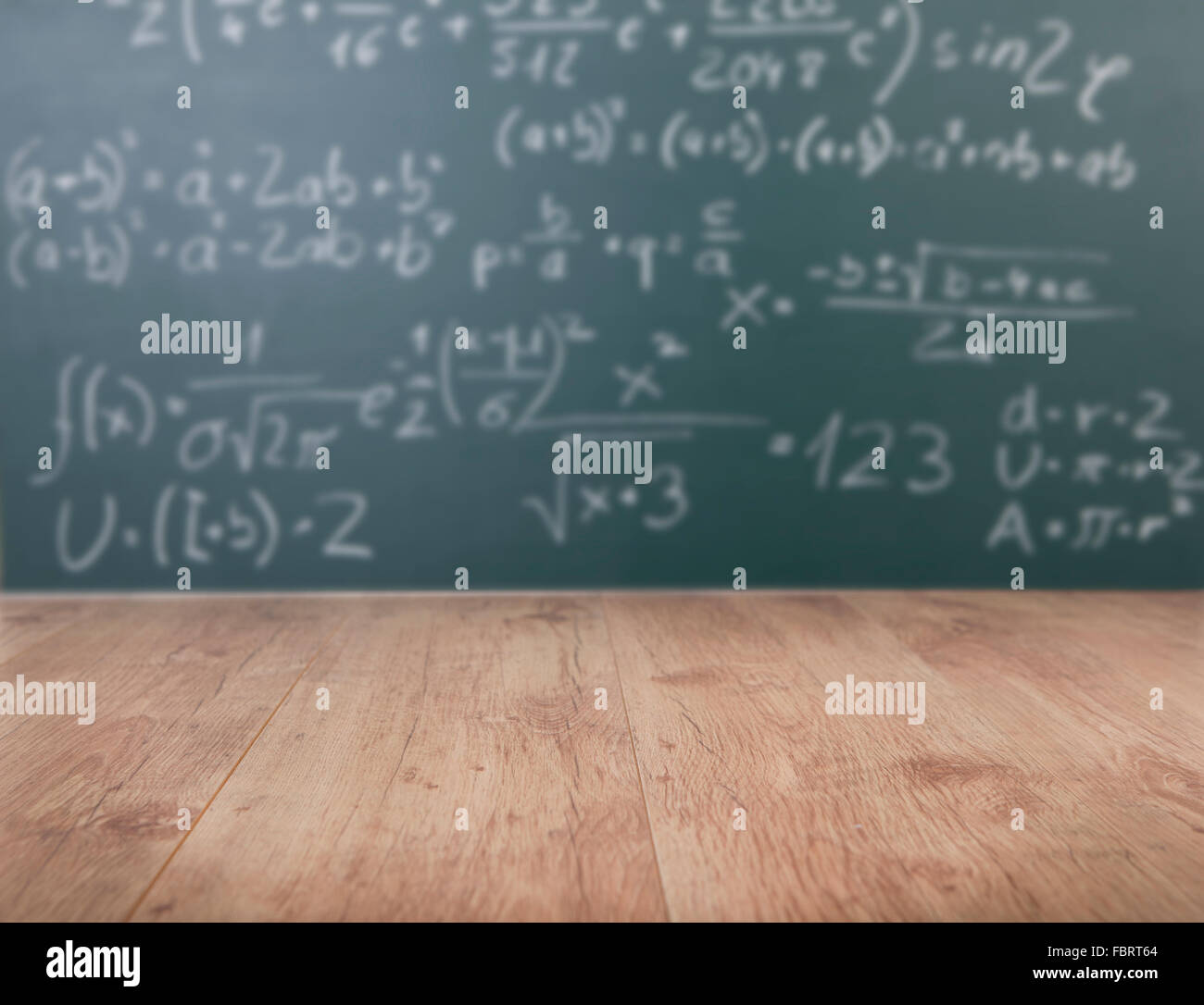 a wooden school desk in front of a green chalkboard with Mathematical formulas Stock Photo