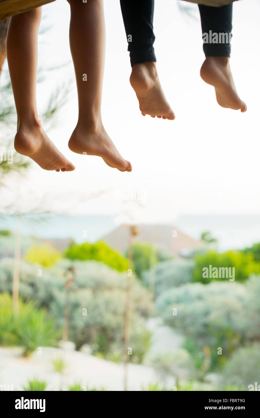 Children sitting side by side with bare feet dangling Stock Photo Alamy