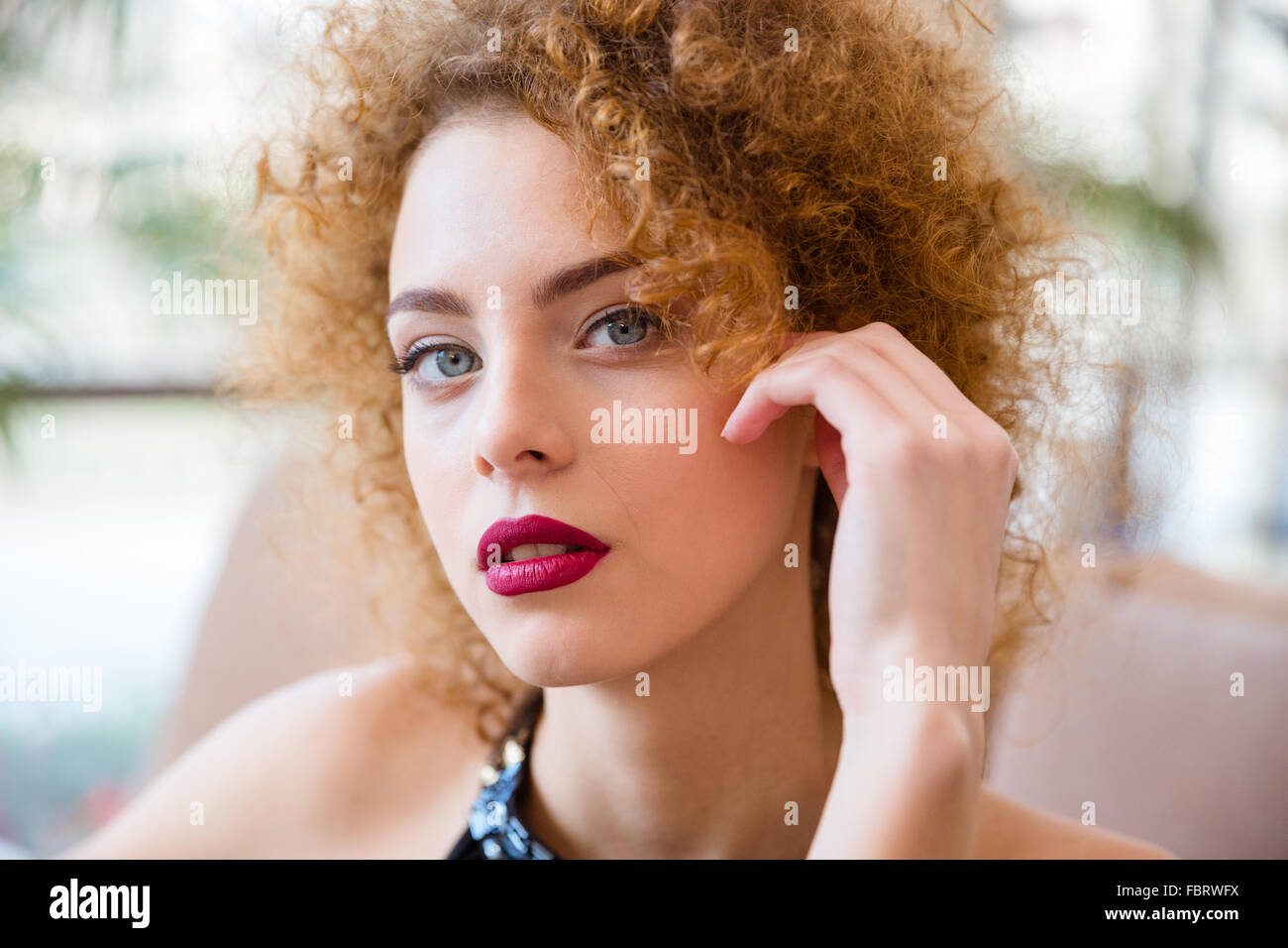 Closeup portrait of a beautiful redhead woman with curly hair looking at camera Stock Photo