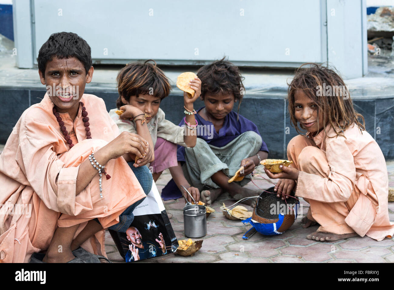 Poor, homeless children eating on the street in Amritsar, India. Stock Photo