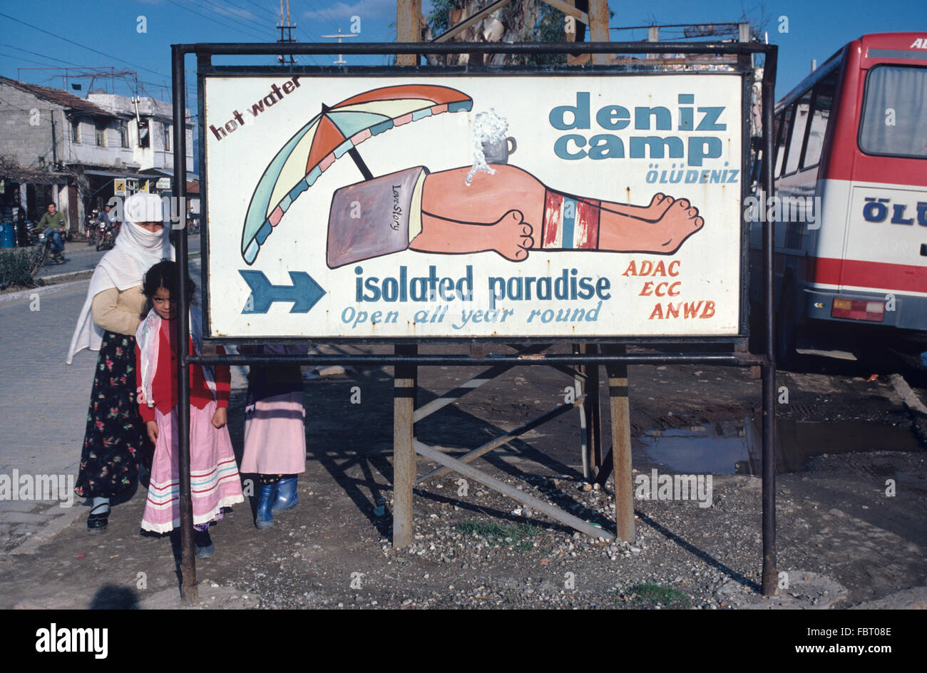 Turkish Woman Wearing Veil and Hotel Sign 'Isolated Paradise' for Deniz Camp at Demizköy, Didim, in Aegean Turkey. Stock Photo