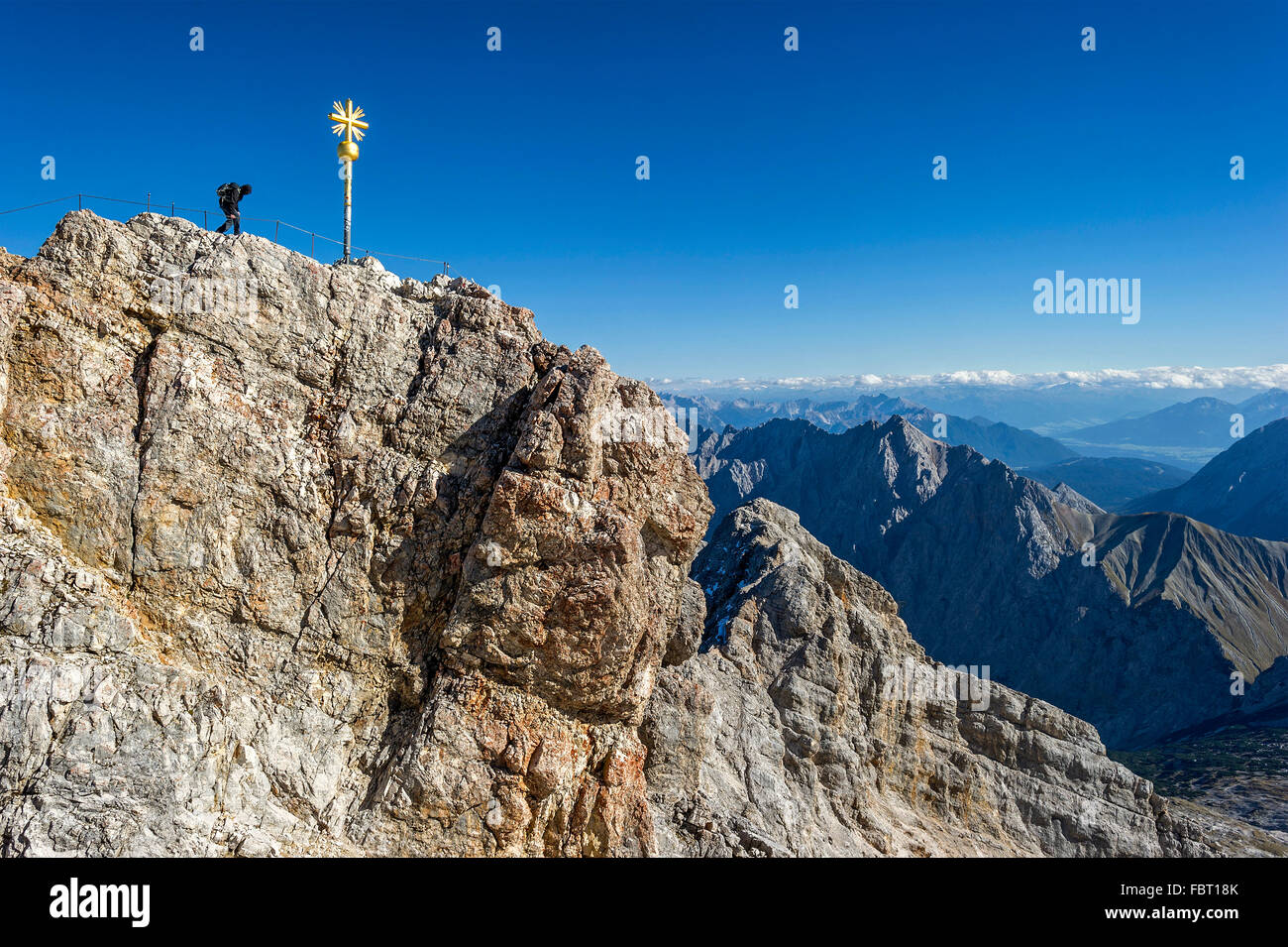 Mountaineer at the summit cross of the Zugspitze, view to the Tyrol, Garmisch-Partenkirchen District, Wetterstein, Alps Stock Photo