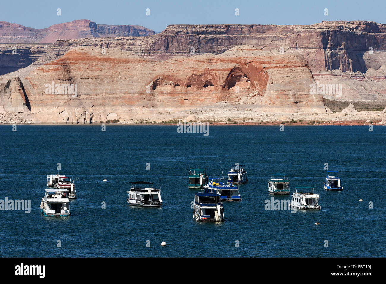 Red Navajo Sandstone cliffs at Lake Powell, houseboats in Wahweap Bay