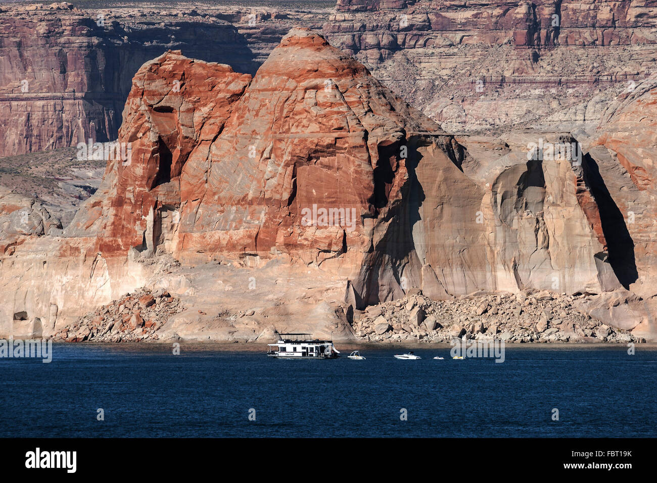 Red Navajo Sandstone cliffs at Lake Powell, houseboat in Wahweap Bay