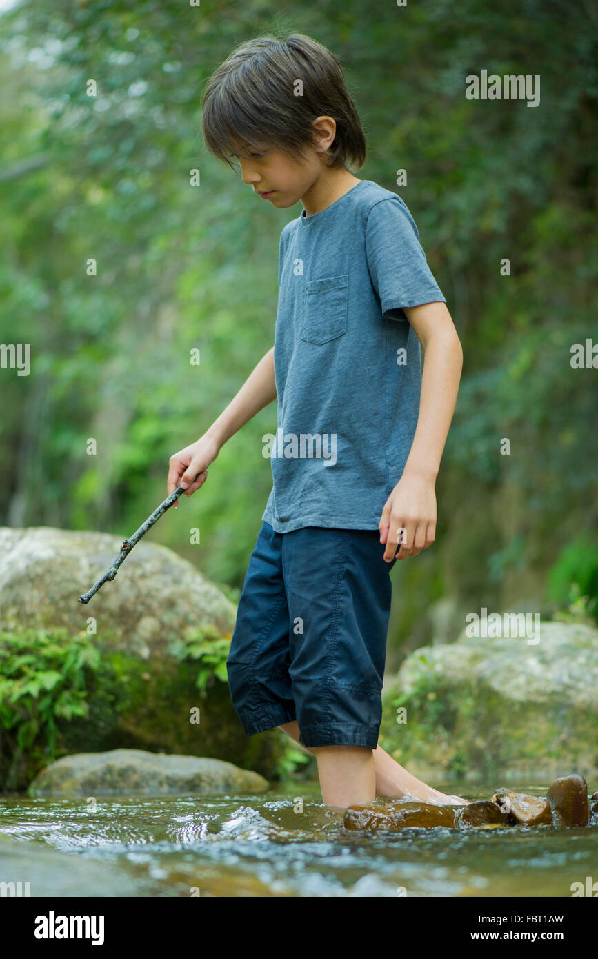 Boy wading in stream Stock Photo