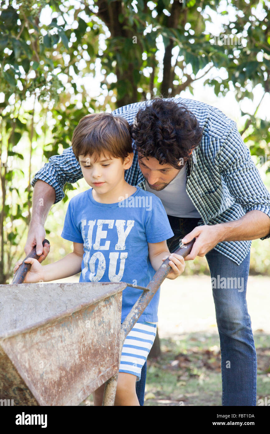 Man teaching young son how to use wheelbarrow Stock Photo