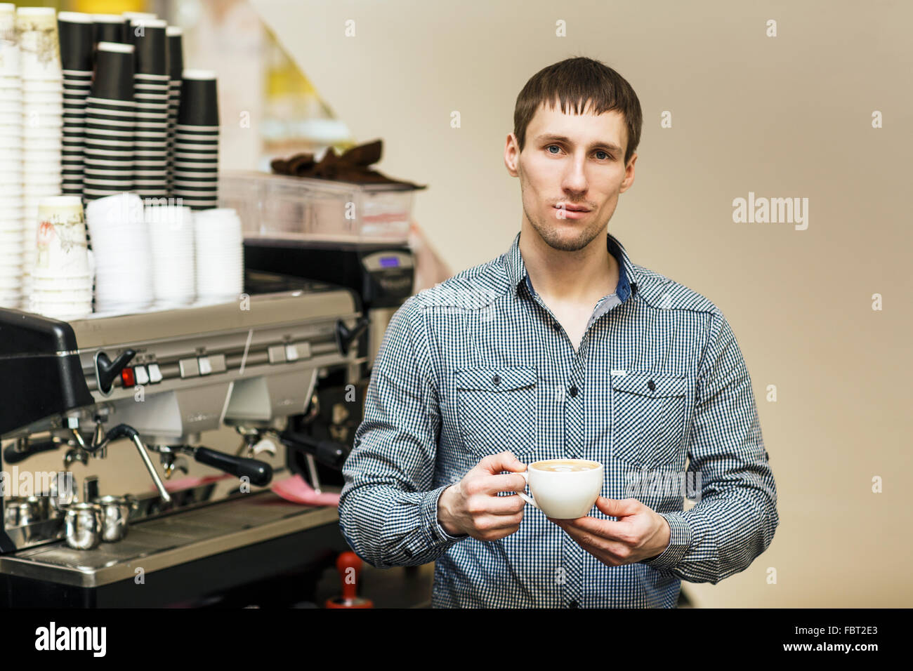 Young barista standing coffee maker on background Stock Photo