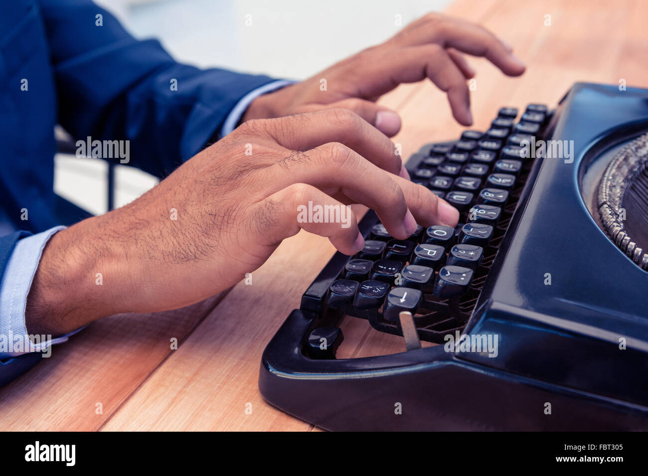 Businessman using typewriter at wooden desk Stock Photo