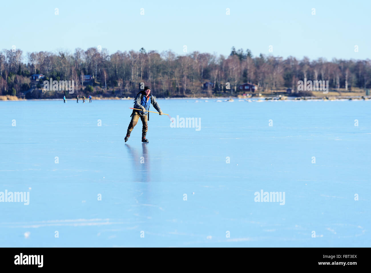 Listerby, Sweden - January 17, 2016: Male senior out for some tour skating. He wears ice claws and an ice pike for safety. Real Stock Photo