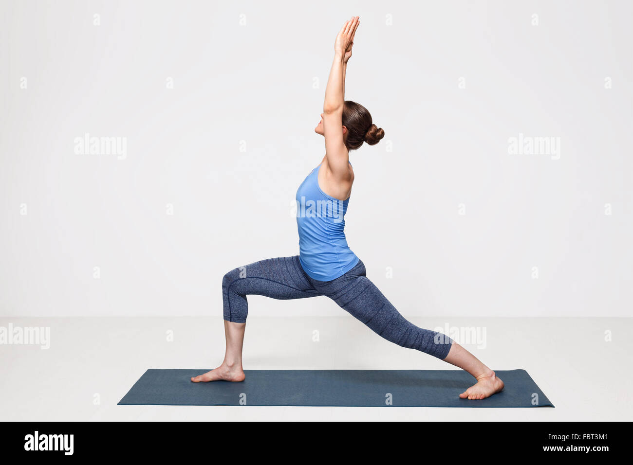 Woman practices yoga asana utthita Virabhadrasana Stock Photo