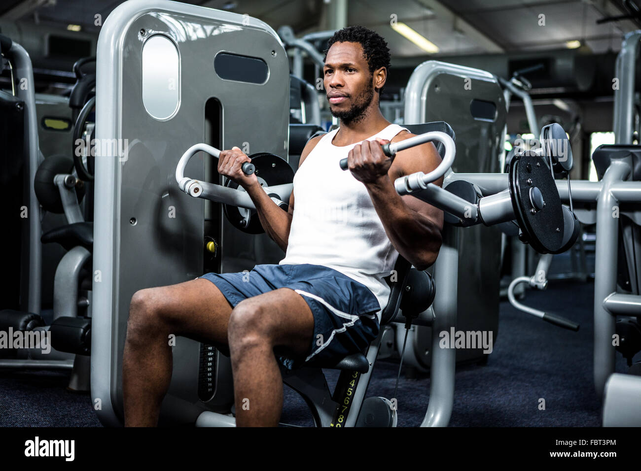 Serious muscular man using exercise machine Stock Photo